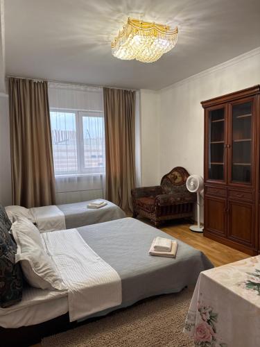 a bedroom with two beds and a chandelier at spacious apartment in Almaty