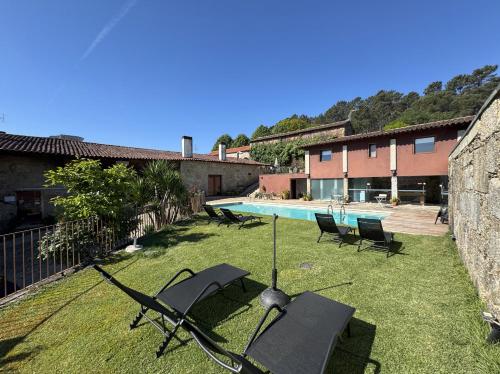 a yard with chairs and a swimming pool at Hotel Rural Alves - BRAGA - Casa Alves de Torneiros in Braga