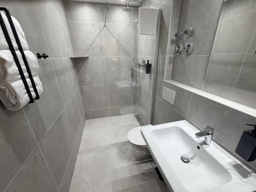 a bathroom with a sink and a shower and a toilet at AS-Hotel NOM in Northeim