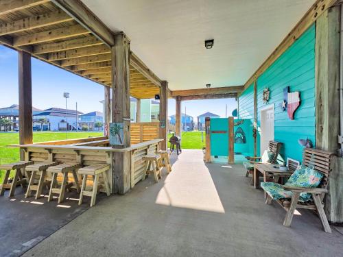 a patio with chairs and tables and a blue building at It's a Shellabration home in Crystal Beach