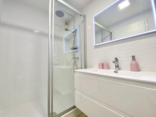 a white bathroom with a shower and a sink at Ksenija Deluxe Residence in Tučepi