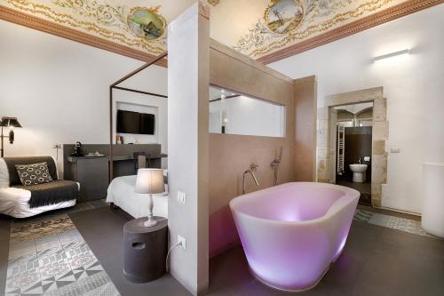 a bathroom with a large tub and a bedroom at Iblainsuite in Ragusa