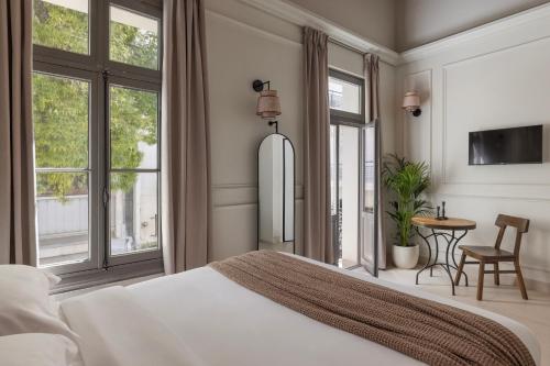 a bedroom with a bed and a table and windows at Airy Athens Suites in Athens