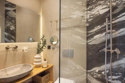 a bathroom with a sink and a glass shower at Airy Athens Suites in Athens