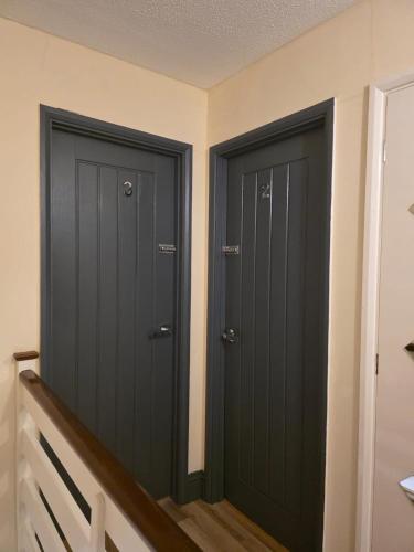 two black doors in a room with stairs at Reading West Homestay in Reading