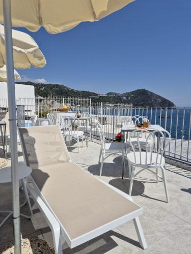 a group of chairs and tables and an umbrella at Casa Borgo Sant'Angelo in Sant'Angelo D'Ischia