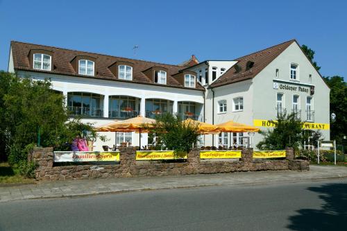 a large white building with orange umbrellas in front of it at Hotel Goldener Fasan in Oranienbaum-Wörlitz