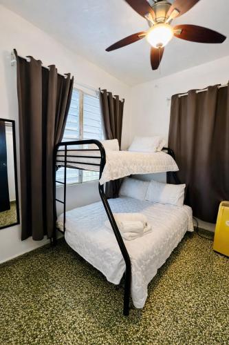 two bunk beds in a room with a ceiling fan at Emmanuelli Sur 7 Bedroom Mall of San Juan Home in San Juan