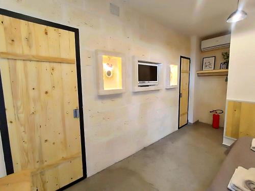 a room with a wooden wall with a tv and a door at Minuetto 60 in Ostuni