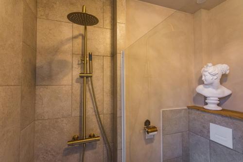 a bathroom with a shower with a statue in it at Villa Hermès in La Flocellière