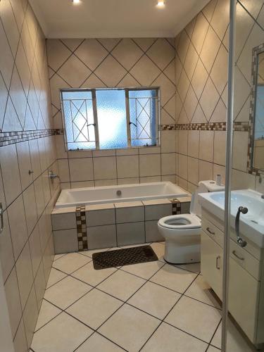 a bathroom with a tub and a toilet and a sink at Eagle Empire in Vereeniging