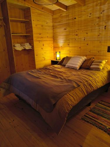a bedroom with a bed in a wooden room at Alma de Puelo in Lago Puelo