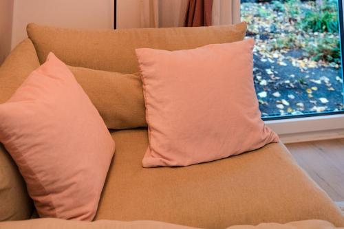 a couch with two pillows sitting next to a window at Stivolles Ambiente in Niendorf! in Hamburg