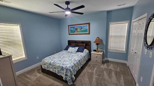 a blue bedroom with a bed and a ceiling fan at Charming Condo 2min Walk From The Famous Boardwalk in Myrtle Beach