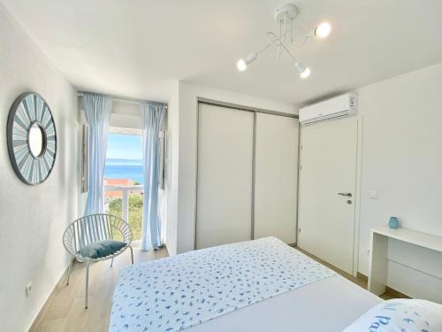 a bedroom with a bed and a chair and a window at Ksenija Deluxe Residence in Tučepi