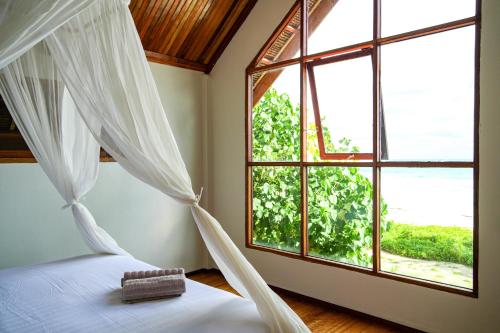 a bedroom with a bed and a large window at Villa Ombak in Katiet
