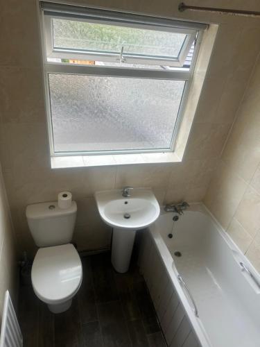 a bathroom with a toilet and a sink and a window at Quiet room 5 in Coventry