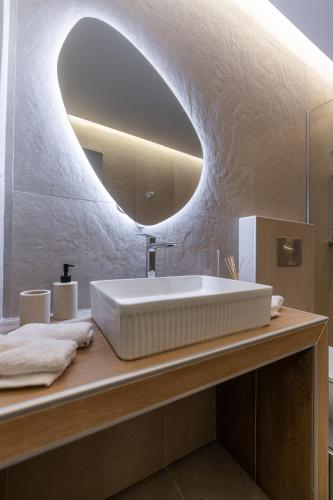 a bathroom with a white sink and a mirror at Enclave Luxury Apartments in Áyios Kírikos