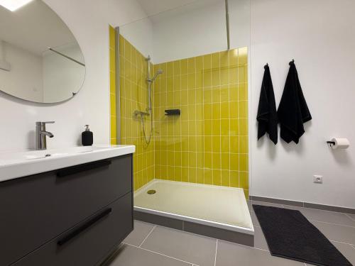ein Badezimmer mit Waschbecken und Dusche mit gelben Fliesen in der Unterkunft Lenne Studio in Lennestadt