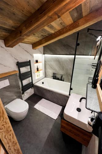 a bathroom with a tub and a toilet and a sink at KITZALPEN Pension in Hollersbach im Pinzgau