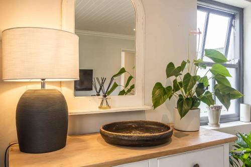 a table with a lamp and a mirror and a plant at Maroon Belles in Cape Town