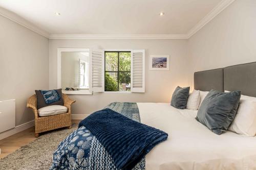 a bedroom with a bed and a chair and a window at Maroon Belles in Cape Town