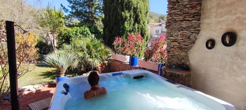 a woman sitting in a hot tub in a yard at Mas des Coccinelles in Mollans-sur-Ouvèze