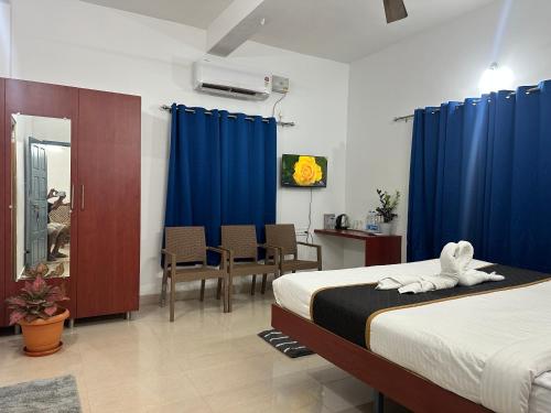 a bedroom with two beds and blue curtains at Joy Villa Homestay in Honāvar