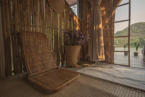 a wicker chair sitting in a room with a window at Royal mountain Hut in Ratchaburi