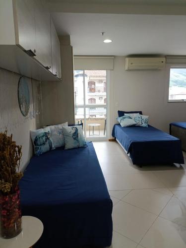 two beds in a room with blue sheets at Inefável flat Porto Marina Resort in Mangaratiba