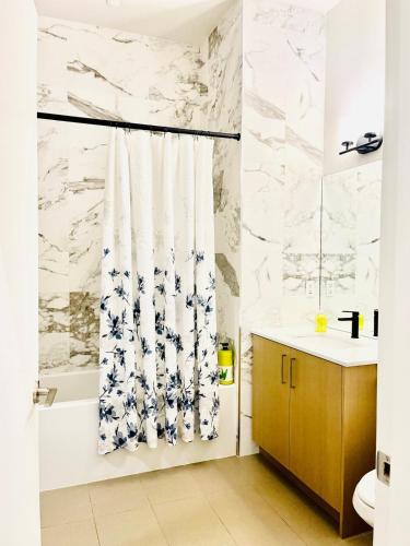 a bathroom with white marble walls and a shower curtain at Modern Ground Level 1BR Apartment - Prime Location in North Vancouver