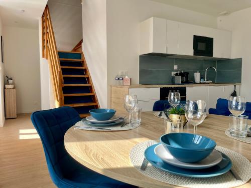 a dining room with a table and blue chairs at Duplex d Iroise rénové 2 chambres Centre Gouesnou Parking & Wifi in Gouesnou