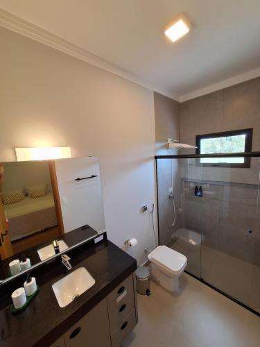 a bathroom with a sink and a toilet and a mirror at Casa Arara in Espirito Santo Do Pinhal