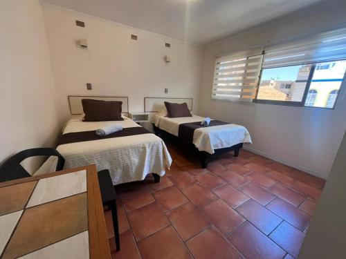 a room with two beds and a window in it at Hotel Brasil in Antofagasta