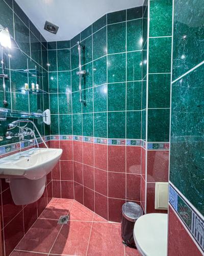 a green tiled bathroom with a sink and a toilet at Family Hotel Chiplakoff in Burgas