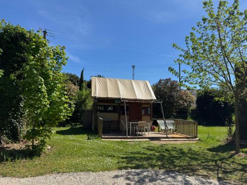 a small house with a tent in a yard at Camping Bois et Toilés in Peyraud
