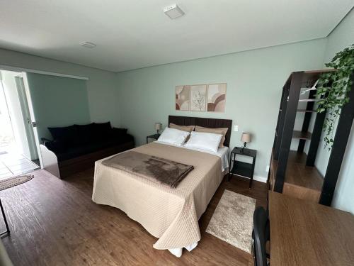 a bedroom with a large bed and a couch at Aconchego do Lago in Espirito Santo Do Pinhal