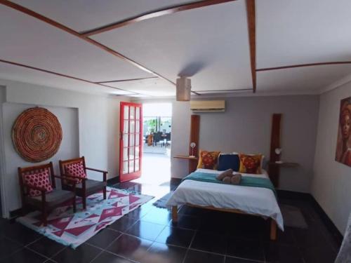 a bedroom with a bed and two chairs in it at Urban Farm Haus Guesthouse in Rundu