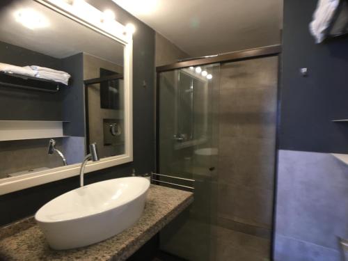 a bathroom with a white sink and a shower at Beira Mar Suite in Fortaleza