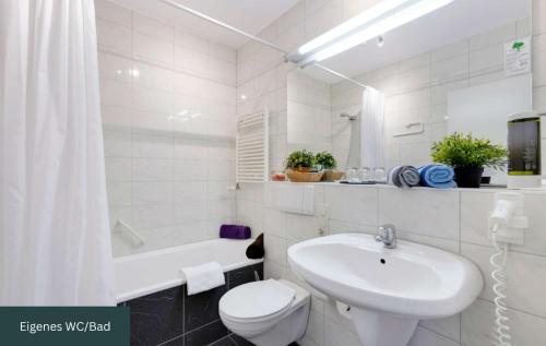 a white bathroom with a toilet and a sink at MONTAGO Monteur-Apartmenthaus Frankfurt Airport in Neu Isenburg