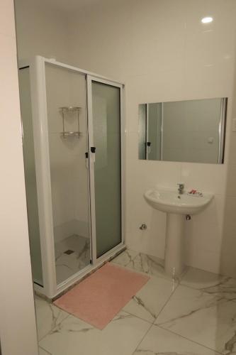 a bathroom with a glass shower and a sink at Guest House RosAmado in São Filipe
