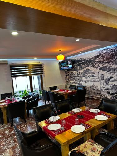 a restaurant with tables and chairs and a mural at Oda Kuksit Hotel in Kukës