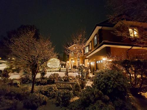 Villa Bellissimo FranTalia - Galleríseum RenáiClássico Beautéssera في كيلونا: منزل مغطى بالثلوج في الليل مع الأضواء