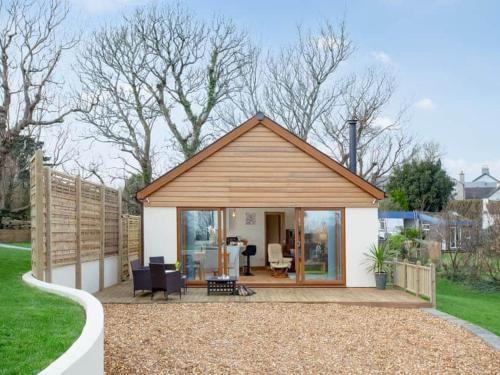 a small shed with a porch and chairs in a yard at Gwythendros in Paul