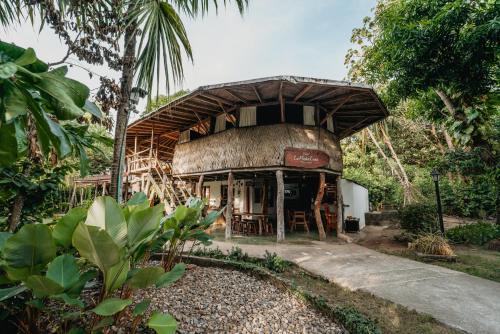 a building with a thatched roof in a forest at Hostal La Media Luna Palomino in Palomino