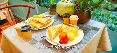 a table with two plates of food and orange juice at Breeze Alley Inn-English services-3mins walk to Park-12mins to Hub-Breakfast,Coffee,Laundry&Tickets in Zhangjiajie