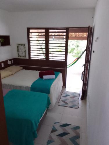 a bedroom with two beds and a door with a window at Pousada e Hostel Praia do poço in Cabedelo