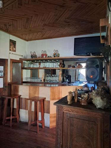 a kitchen with a bar with two stools and a tv at Hotel Anjara in Ambositra