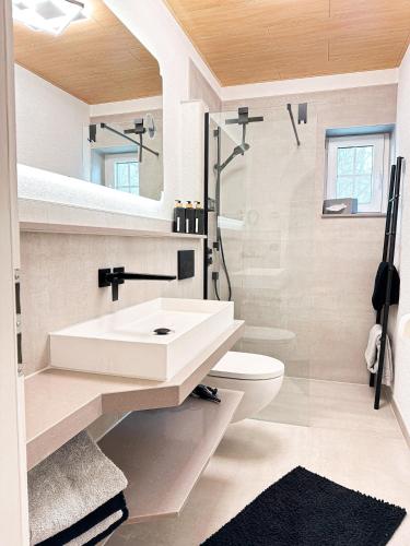 a white bathroom with a sink and a toilet at Harz-Fewo Weitsicht, modern & ruhig mit 2 Balkonen, Jura Kaffeevollautomat, Kaminofen, Gäste mit Hund willkommen in Bad Harzburg