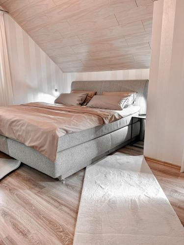 a bedroom with a large bed with a wooden ceiling at Harz-Fewo Weitsicht, modern & ruhig mit 2 Balkonen, Jura Kaffeevollautomat, Kaminofen, Gäste mit Hund willkommen in Bad Harzburg